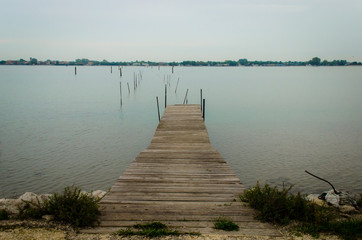 Fototapeta premium Un molo di legno si protende sull'acqua dell'isola di Sant'Erasmo nella laguna di Venezia