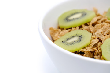 Cereal flake with green kiwi fruits in the white bowl isolated on white background
