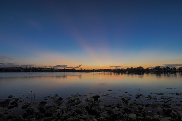 Lake view evening above Lotus lake with orange sun light and blue sky background, sunset at Krajub Reservoir, Ban Pong District, Ratchaburi, Thailand.