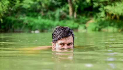 Fototapeta premium Man enjoy swimming in river or lake. Summer relax. Wild and free concept. Summer activity. Swimming sport. Freshness of wild nature. Summer vacation. Relaxation and rest. Refreshing feeling