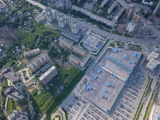 Panoramic aerial view of a large shopping center with parking where there are many cars in Novosibirsk on a summer afternoon at sunset. Industry and construction.