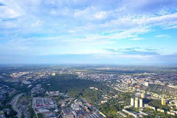 Obraz premium Widok z lotu ptaka na panoramę miasta z wieloma domami i budynkami w pogodny letni dzień pod błękitnym niebem z szarymi chmurami w Nowosybirsku.