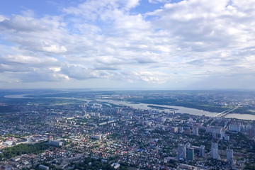 Aerial view of the cityscape with a lot of houses, two bridges, river and buildings on a summer clear day under a blue sky with gray clouds in Novosibirsk.