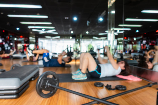 Blur Fitness class with group of people excercising with barbell, dumbbell