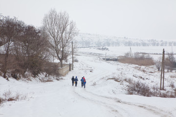 Fototapeta na wymiar group of boys going on the snowy country road 