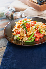 Traditional Thai food papaya salad prepared with fine slices of papaya, tomatoes, green beans and peanuts.
