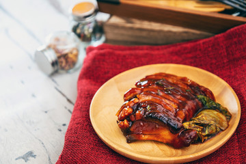 Chinese lacquered pork slices with its caramelized sauce prepared for eating in a wooden plate