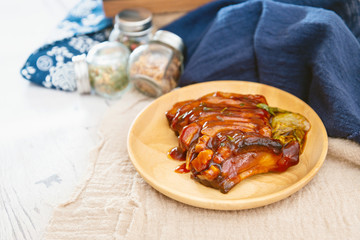 Chinese lacquered pork slices with its caramelized sauce prepared for eating in a wooden plate