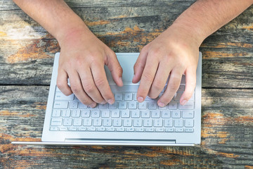 business, education, people and technology concept. Close up of men hands with laptop keyboard on wooden table background. Top view.