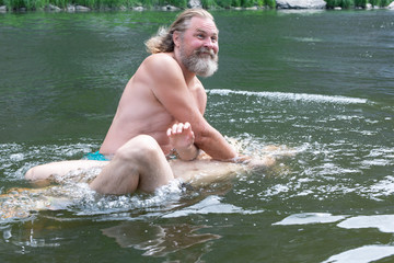 a bearded man with a kind face dips a man in the water. rite of blessing, baptism. Ceremony Of A...