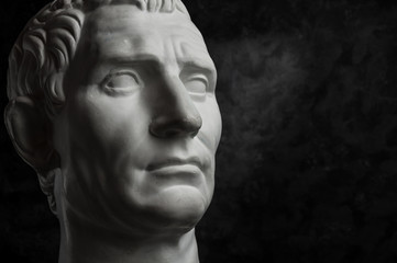 Gypsum copy of ancient statue Augustus head on dark textured background. Plaster sculpture man face. - obrazy, fototapety, plakaty