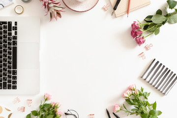 White workspace with laptop, mug of coffee, flowers, stationery on white background