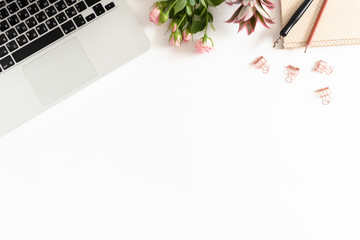 Flatlay of laptop, flowers, stationery on white background with copy space