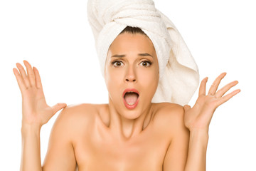 Young beautiful shocked woman with towel on her head on white background