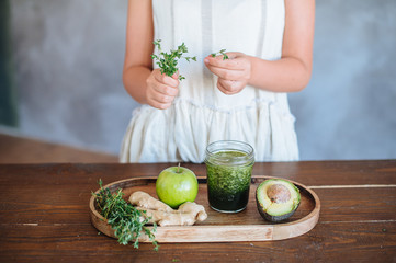 woman with green smoothie In hand on wooden rustic table. Green healthy food, vegetarian, clean eating concept. Top view, copyspace