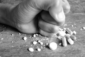 Hands clenched on a multicolored drug placed on a wooden table