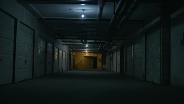 A big dirty parking garage under the flickering lights