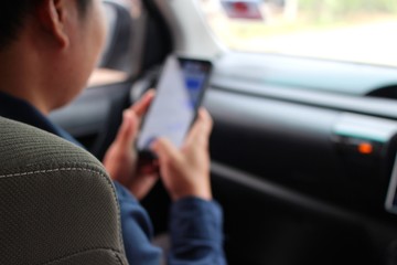The young man is using a mobile phone while on a car, in low light, shooting blurred images