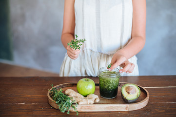 woman with green smoothie In hand on wooden rustic table. Green healthy food, vegetarian, clean eating concept. Top view, copyspace