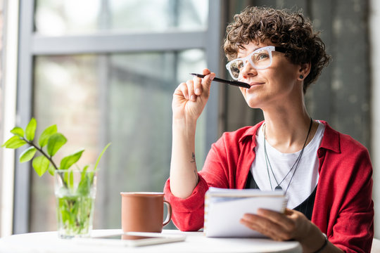 Young pensive female in eyeglasses thinking of new creative ideas