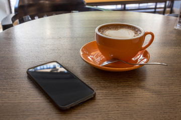 Coffee, donut and smartphone on a wooden table in cafe