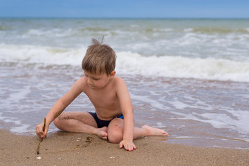Fototapeta na wymiar A little boy plays near the water by the sea.