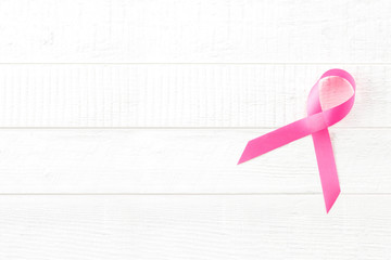 Satin pink ribbon symbol on white wood background, breast cancer awareness campaign