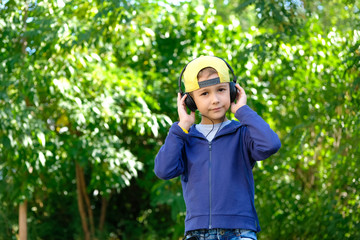 A young boy in headphones listening to modern music in nature. Children's song.