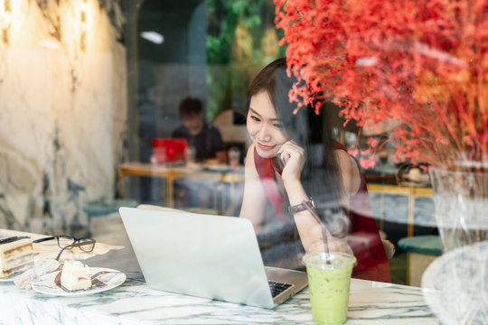 Social connection and lifestyle concept - Young attractive woman smiling using smartphone and laptop for social online communication and contact in coffee shop