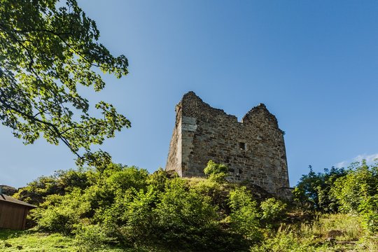 Primda, Czech Republic - August 11 2019: Old ruin of oldest stone castle in the Czech Republic, from 12th century, standing on a hight hill on a rock. Sunny summer day with blue sky and green trees.