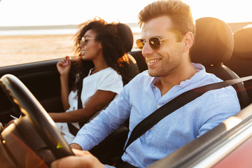 Beautiful young multiethnic couple riding in a convertible