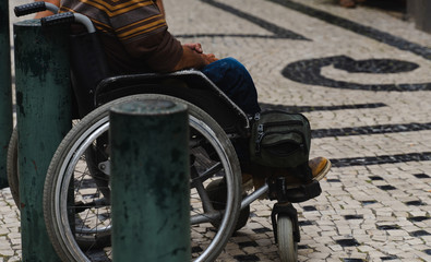 senior man sitting on the wheelchair outdoors. old senior hands closeup.. social issues.