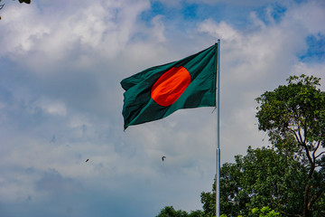 National Flag of Bangladesh. The red green flag is flying in the blue sky of Bengal.