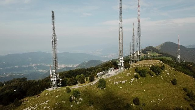 Drone aerial view of a group of towers for telecommunications, television broadcast, cellphone, radio and satellite on Linzone mountain peak. Electromagnetic and environmental pollution. Italian Alps