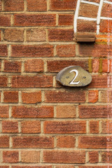 House number 2 on a wooden sign on a brick wall