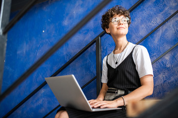 Happy young modern student or manager in casualwear using laptop