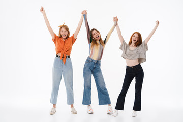 Obraz premium Portrait of three young girls wearing casual clothes smiling and raising arms together