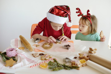 Two cute girls making cookies for Christmas. Children bake ginger biscuits.