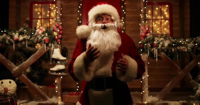 Santa Claus emotionally talks and emotionally gesticulating standing near his house decorated for Christmas and listens to the answer.