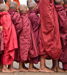Fototapeta premium young buddhist pilgrims dressed in red traditional robes waiting to receive merit in myammar