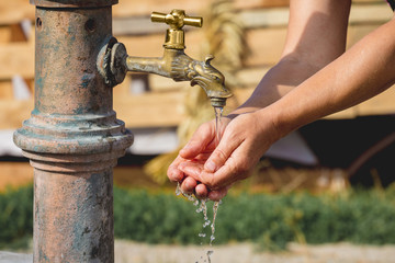 Woman washes her hands under the tap on the street_