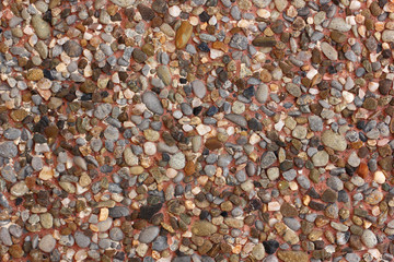 Background wall lined with small stones of different shapes on pink cement.