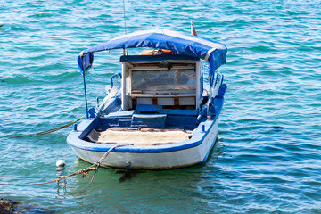 Old blue and white colored boat in clear turquoise colored  water in Izmir in Turkey.