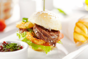 Gourmet, restaurant, delicious dinner food - close up of Sandwich with Beef and Deep Fried Onions Ring, Tomato and Cucumber. Garnished with French Fries