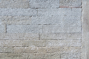 Detail einer alten grauen Steinmauer aus viereckigen, länglichen Steinen mit texturierter Oberfläche