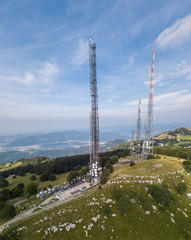 Drone aerial view of a group of towers for telecommunications, television broadcast, cellphone, radio and satellite on Linzone mountain peak. Electromagnetic and environmental pollution. Italian Alps