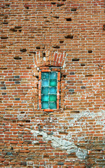 Old red brick wall with a narrow window from glass blocks
