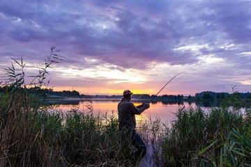 Angler catching the fish during cloudy sunset