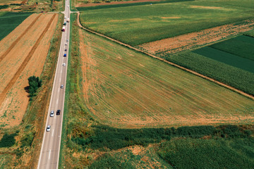 Fototapeta na wymiar Traffic on the road through countryside landscape from drone pov
