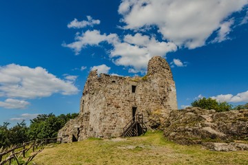 Fototapeta na wymiar Primda, Czech Republic - August 11 2019: Old ruin of oldest stone castle in the Czech Republic, from 12th century, standing on a high hill on a rock. Sunny summer day with blue sky and white clouds.